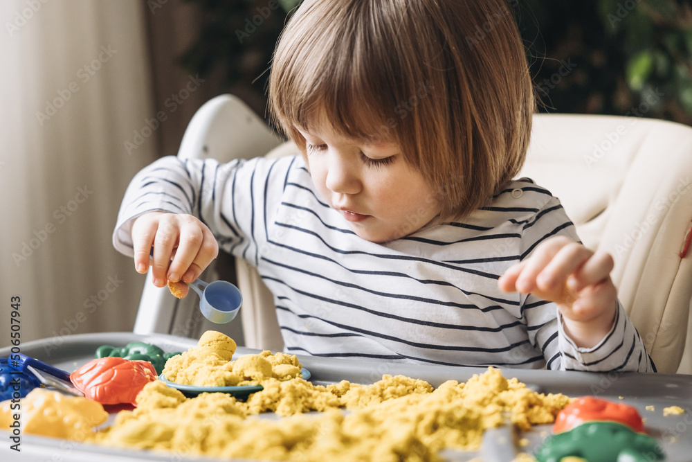 Cute little boy playing with kinetic sand. Development of fine motor skills. Early sensory education. Activities Montessori. Sensory plays at home. Cute little boy playing with kinetic sand. Development of fine motor skills. Early sensory education. Activities Montessori. Sensory plays at home.