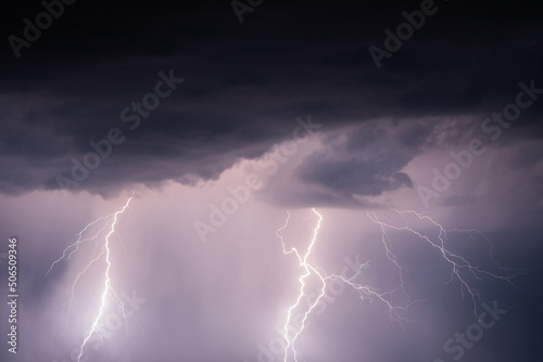Dark stormy sky with lightning strikes and thunderstorm clouds at night. Dramatic, nature, danger, weather and atmosphere concept