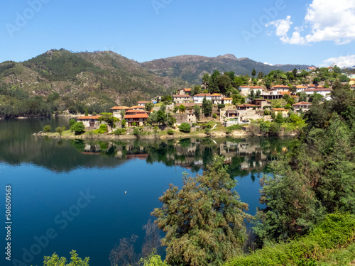 Paisaje con casas reflejándose en el agua de un río. Río Cávado, Parque Natural do Gêres, norte de Portugal.