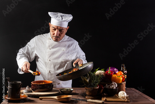 Male chef in white uniform preparing food plate with vegetables