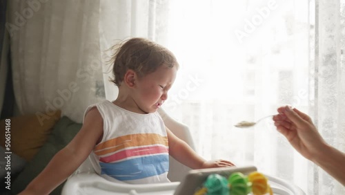 Little blond boy does not want to eat a meal that gives him a parent and cry.