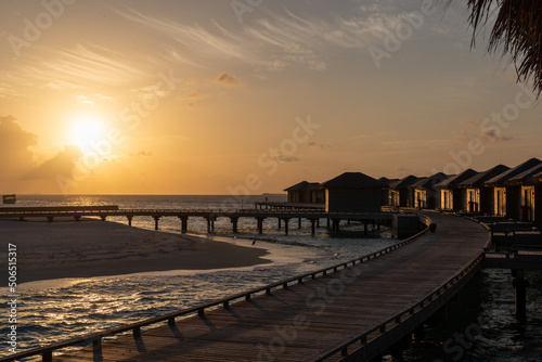 Wooden cabins in Maldives on a blue sea during sunset