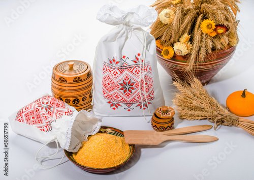 Corn grits in textile bags on a white background in a rustic style. Ukrainian embroidered ornament