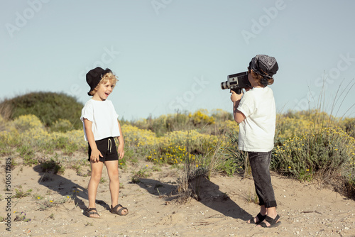 Happy little brothers recording video on beach