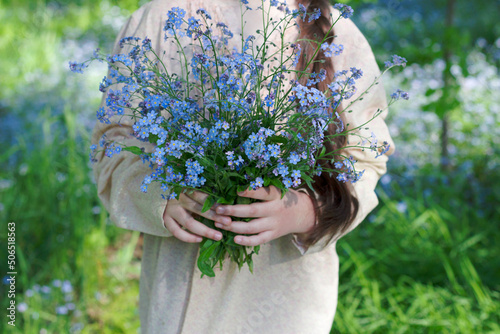 girl hands holding a blue bouquet with forget me not wild fowers