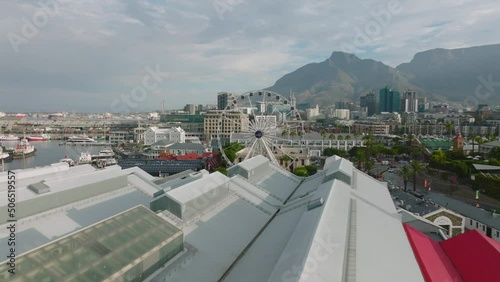 Fly over Victoria Wharf Shopping Centre on waterfront. Revealing The Cape Wheel attraction. Giant observation wheel in Victoria and Alfred Waterfront. Cape Town, South Africa