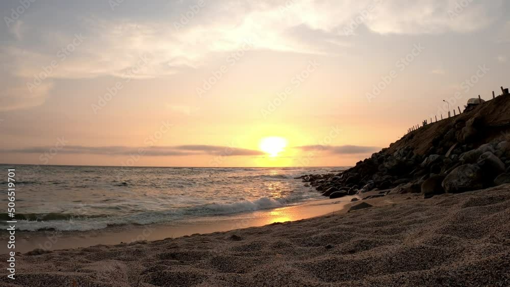beautiful view from the sand of the beach of a sunset with the sea and the sun on the horizon and surfers in the water in 4k beautiful view from the sand of the beach of a sunset with the sea and the sun on the horizon and surfers in the water in 4k