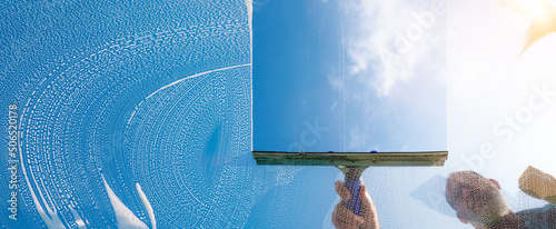 Fotografía Window cleaner cleaning window with squeegee and wiper on a sunny day with a bri