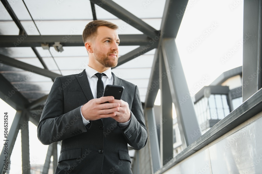 Confident young businessman using cell phone in the city. Confident young businessman using cell phone in the city.