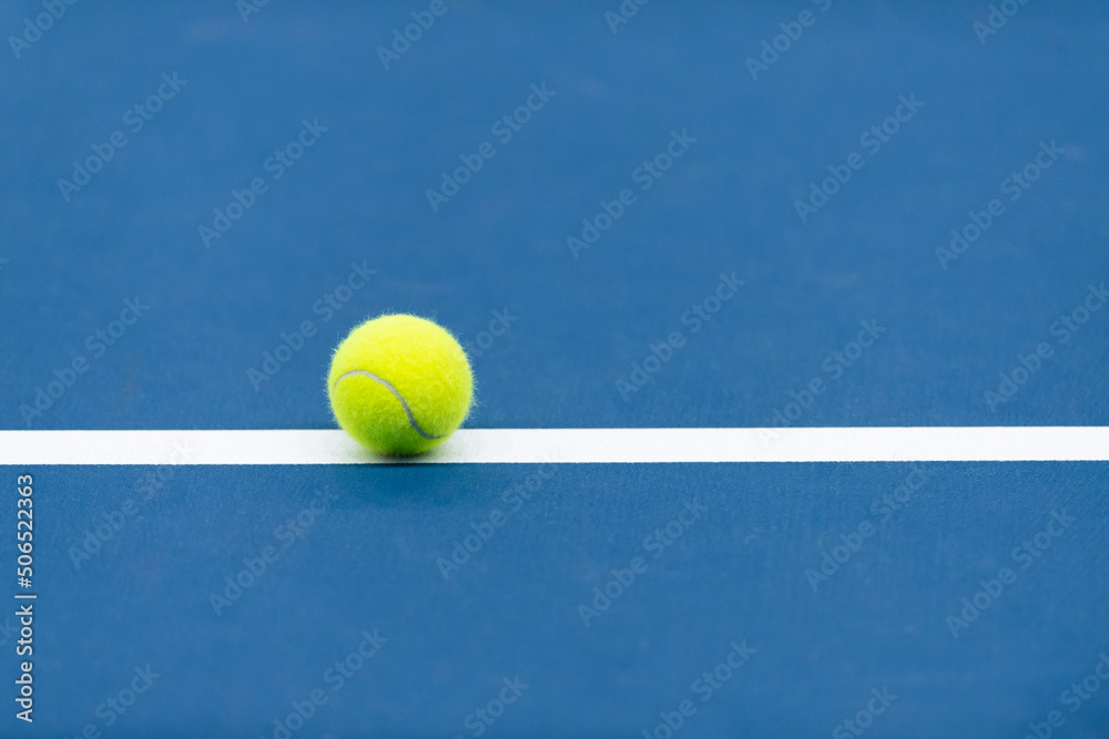 Yellow tennis ball with white line on blue court. Horizontal sport theme poster, greeting cards.