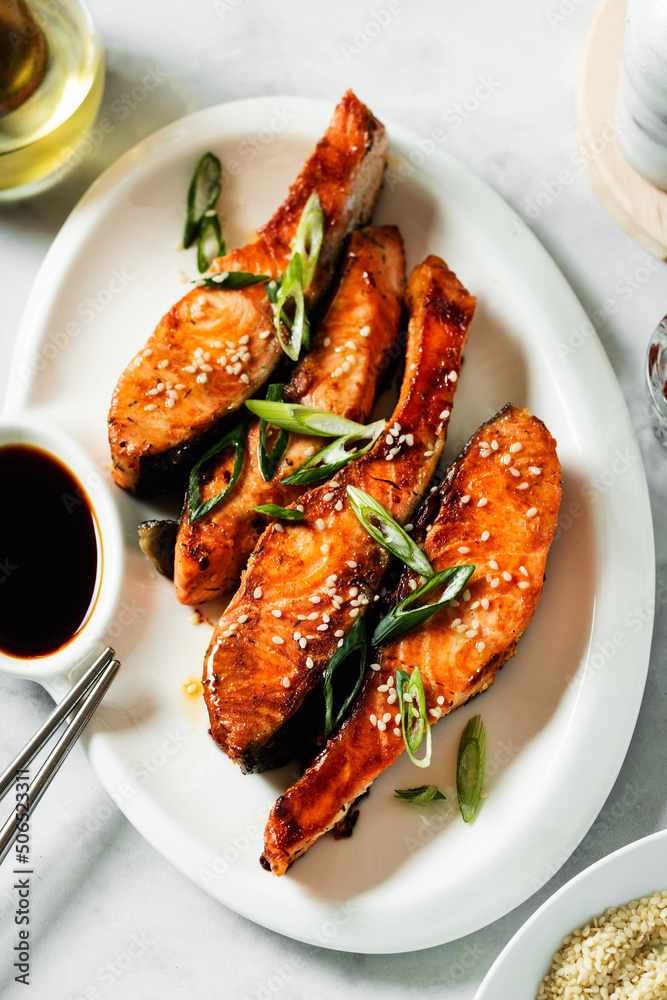 fried pieces of salmon marinated in sweet and sour sauce in a plate with soy sauce. asian food fried pieces of salmon marinated in sweet and sour sauce in a plate with soy sauce. asian food
