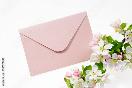 Pink envelope with wedding invitation card or birthday letter decorated with branch of blossom apple tree. Flat lay. Top view.