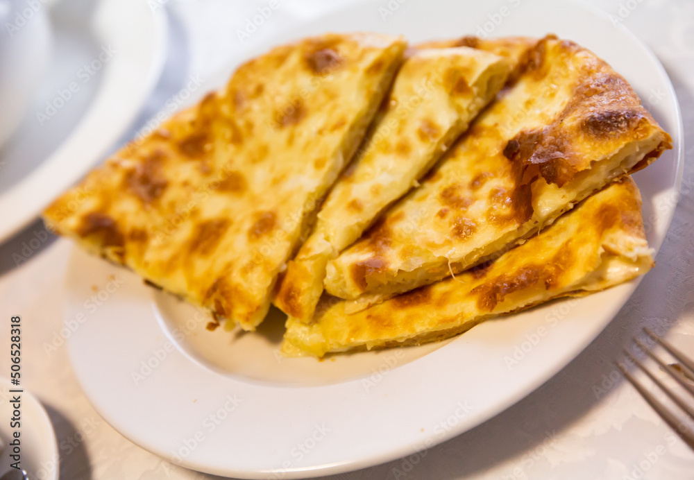 Traditional caucasian megrelian khachapuri, fried pie with cheese on a plate in cafe
