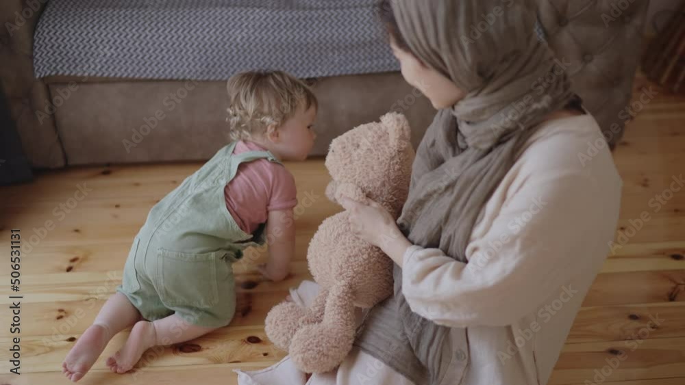 Adorable infant baby boy daughter playing with arabic muslim mom in hijab at home. Happy mixed race family mother and cute little boy son learning funny game having fun enjoying sweet moments together