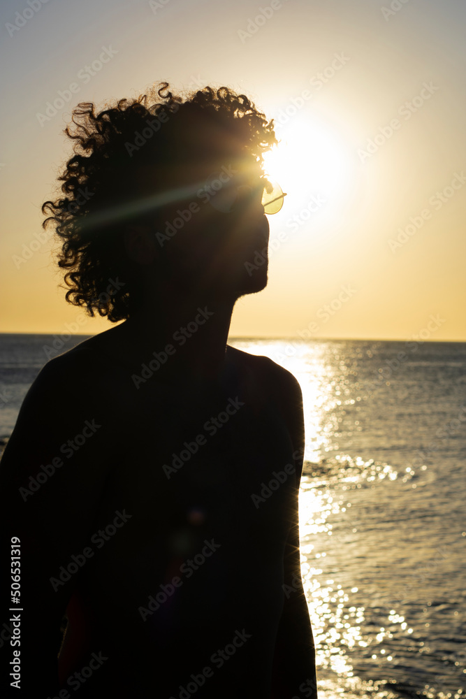 
silhouette of man with afro on the beach at sunset