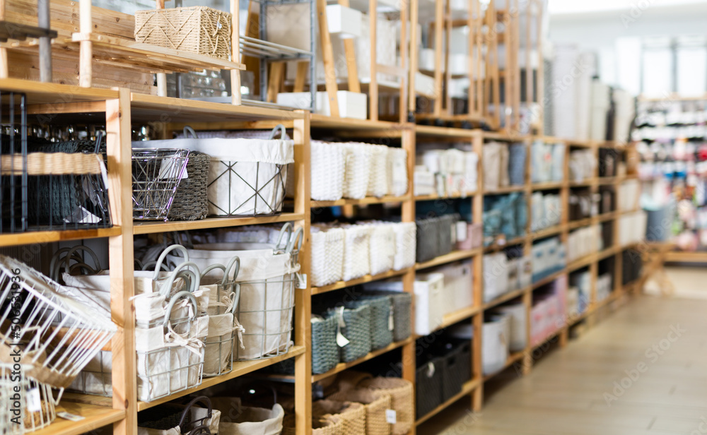 Variety of decorative storage boxes displayed on shelving in household goods store. Concept of goods to organize home space
