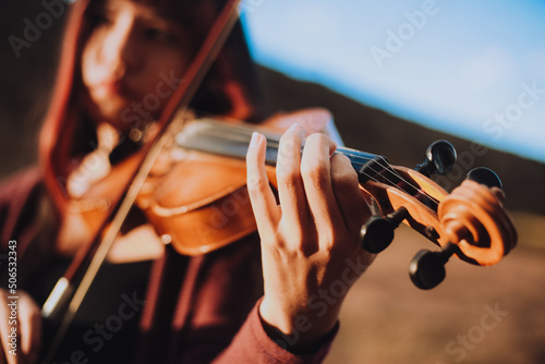 Detalle de Mujer joven tocando violín en una montaña al atardecer. Concepto de personas y música. photo