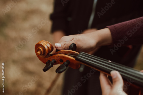 Manos de mujer afinando un  violín en una montaña al atardecer. Concepto de personas y música. photo