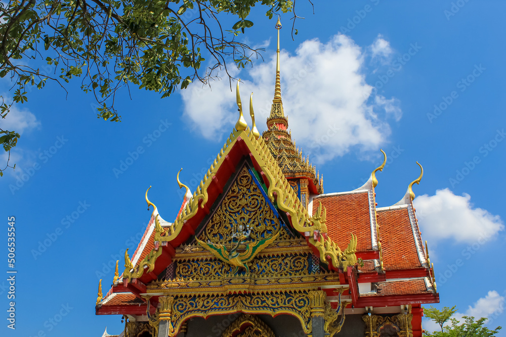 Blue sky with white cloud, copy space for text, tree leaves and the roof of Thai buddhist temple in Phuket, Thailand. Blue sky, copy space for text, wallpaper, golden, red, green
