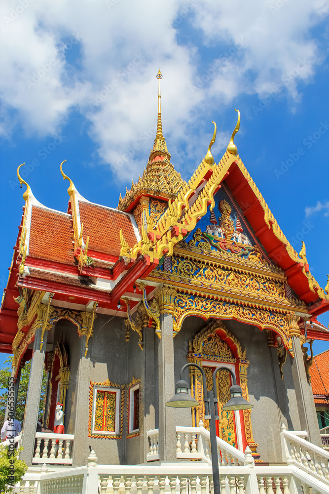 Vertical image of the roof and entrance decoration of Thai buddhist temple in Phuket, Thailand. Blue sky, copy space for text, wallpaper, golden, red, green, blue, background Vertical image of the roof and entrance decoration of Thai buddhist temple in Phuket, Thailand. Blue sky, copy space for text, wallpaper, golden, red, green, blue, background