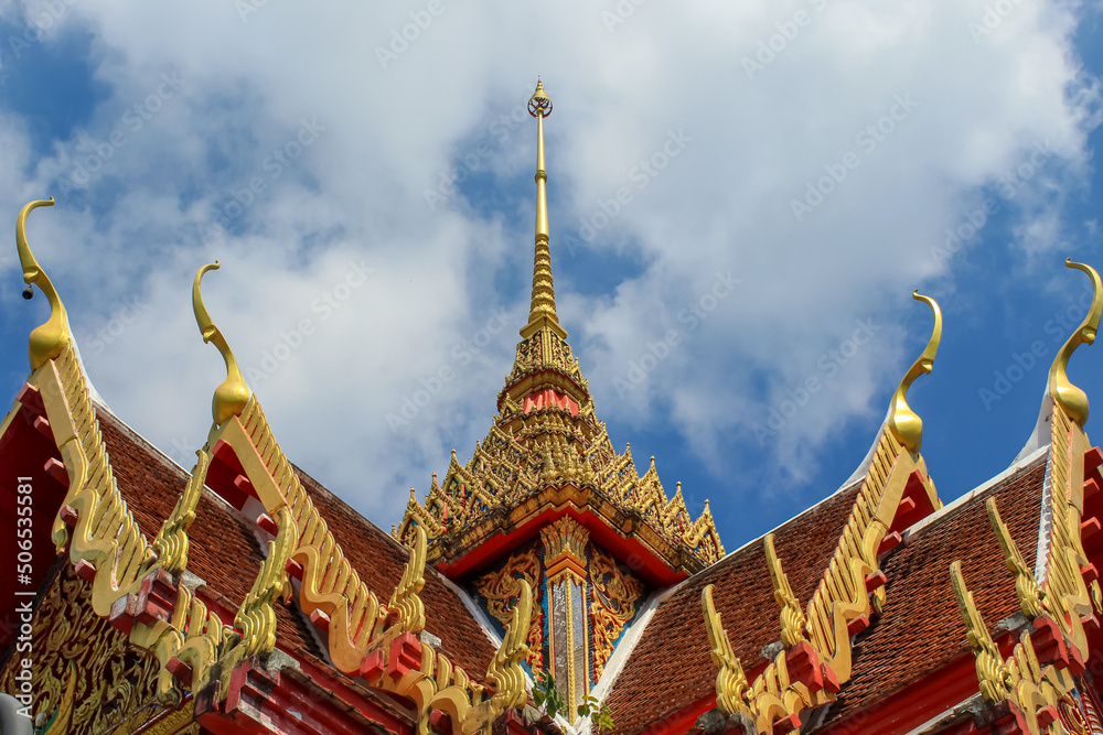 Fototapeta premium The roof of the Thai buddhist temple in Phuket, Thailand. Blue sky, copy space for text, wallpaper, golden, red, green