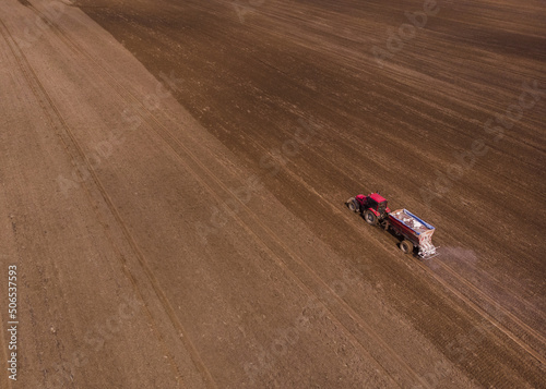 Tractor with fertilizer trailer fertilizes the field after planting. Copy space