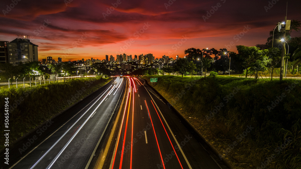 Trail of light caused by vehicular traffic in SP-294, Comandante Joao Ribeiro Barros Highway with buildings from downtown in the background, in Marília,