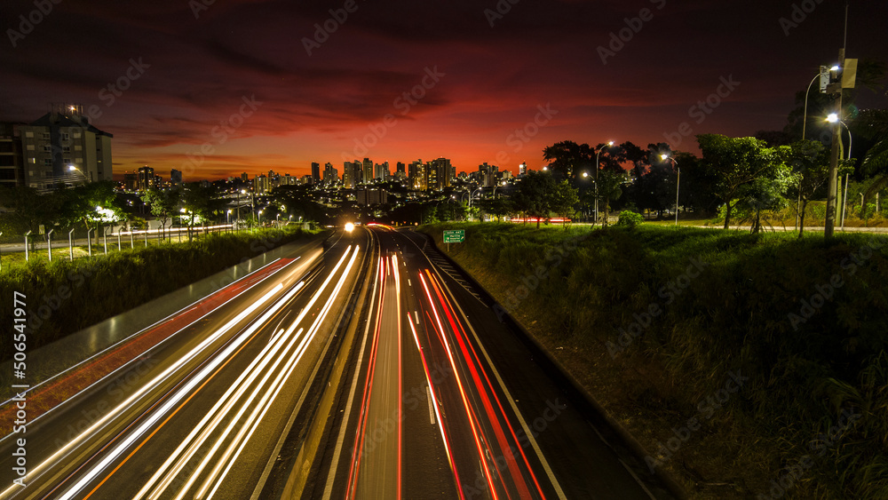 Trail of light caused by vehicular traffic in SP-294, Comandante Joao Ribeiro Barros Highway with buildings from downtown in the background, in Marília,