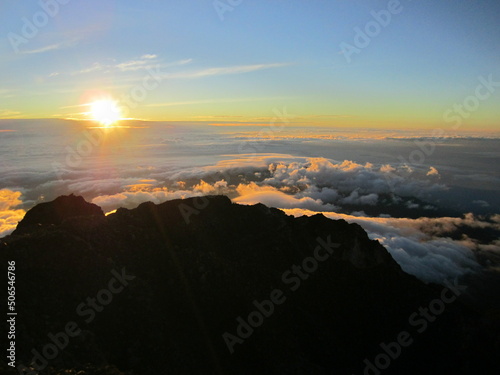 Sunrise at the top of Mount Rinjani in Lombok Island  Indonesia. View of crater lake covered in clouds from the summit. Beautiful sun rising in the horizon.