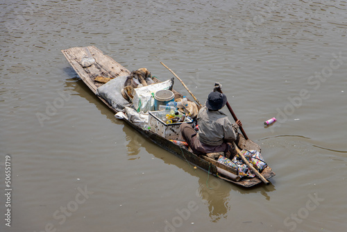 Photography A poor human floats on an old boat full of recycled materials