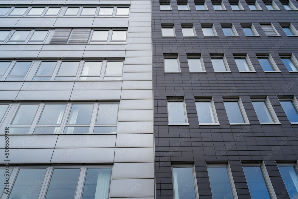 Two office buildings together with a light and dark gray facade and many windows Two office buildings together with a light and dark gray facade and many windows