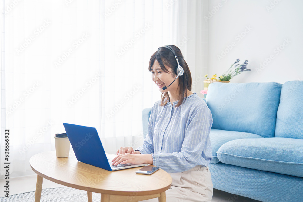 リビングでノートパソコンでビデオ通話する女性 リビングでノートパソコンでビデオ通話する女性