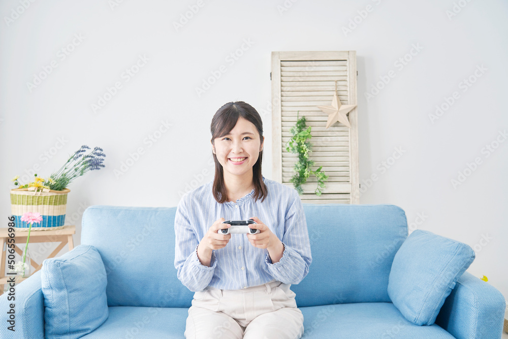 Obraz premium リビングで笑顔でテレビゲームをする女性