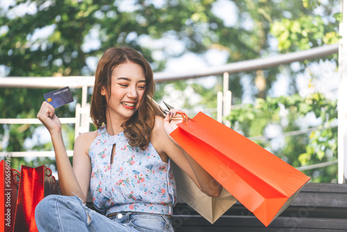 Happy young adult southeast asian woman with shopping bags on day