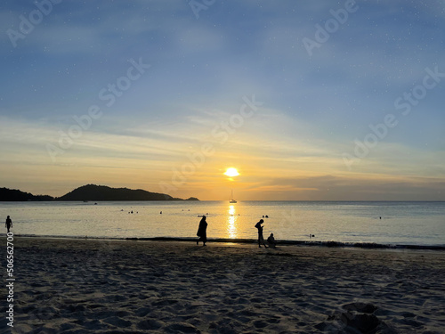 Beautiful starry sky with clouds. Sunset glow in the evening sky. People swim in the sea and walk along sandy shore. Tropical beach. Sunset. Amazing scenery Seascape. Silhouettes of people. Reflection