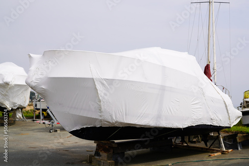 boat out of water protected by a plastic film for wintering ship under tarpaulin tarp photo