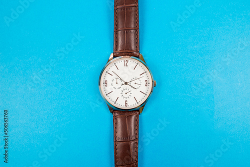 Close-up of a man's wrist watch isolated on a blue background.