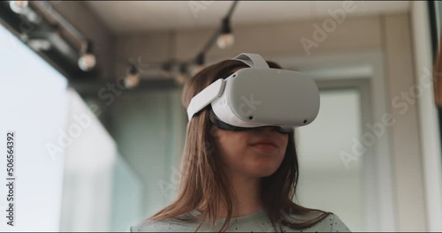Close up of young woman looking around wearing vr goggles viewed from under