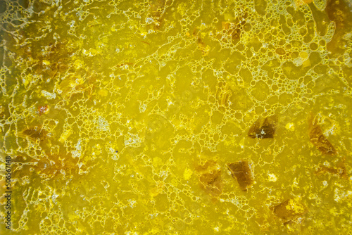 The texture of the surface of a yellow vegetable soup with droplets of fat on the surface.