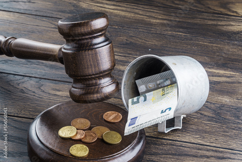 Gavel and mug with money. Alms prohibition or charity fraud concept photo