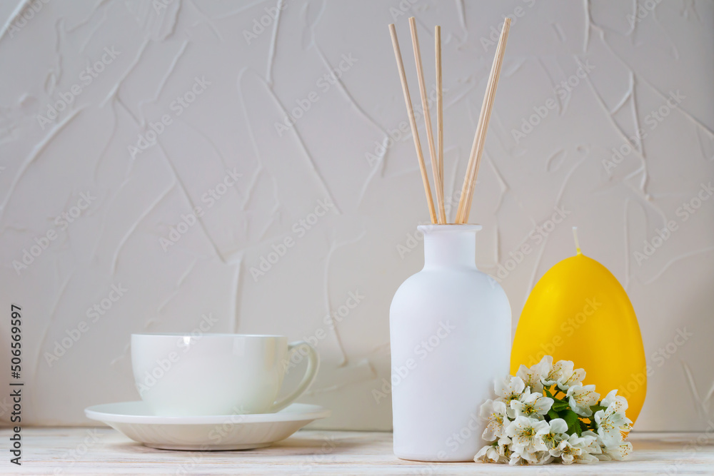 Aromatic reed diffuser on a white background with flowers, candle and ...