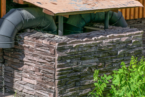 Schilderij op canvas Exhaust ventilation pipes enclosed by a stone wall on a spring morning