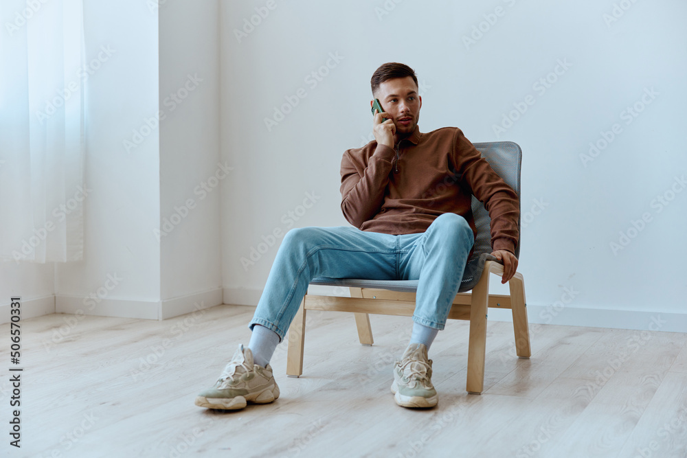 Serious happy focused young tanned man guy talk in call with friends discusses latest news looks aside sitting in chair at home. Distance communication Gadget using concept. Copy space for ad Serious happy focused young tanned man guy talk in call with friends discusses latest news looks aside sitting in chair at home. Distance communication Gadget using concept. Copy space for ad