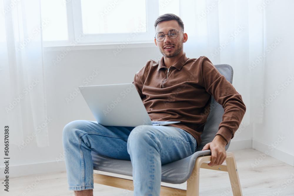 Modern Profession offer. Happy cheerful guy man in eyewear touch chair smile project think about right decision for work screen sitting in chair at home. Remote Job Distant Work Communication concept