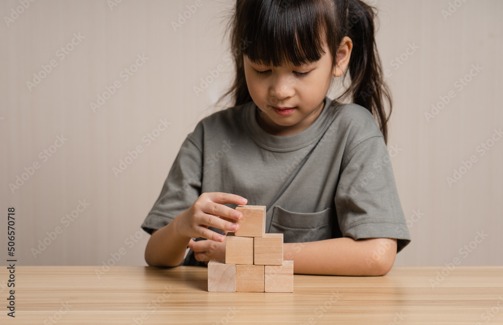 Girls build wooden cubes in layers with wooden blocks cube wooden box. girl playing with wooden block toys. Concept of early child development Girls build wooden cubes in layers with wooden blocks cube wooden box. girl playing with wooden block toys. Concept of early child development