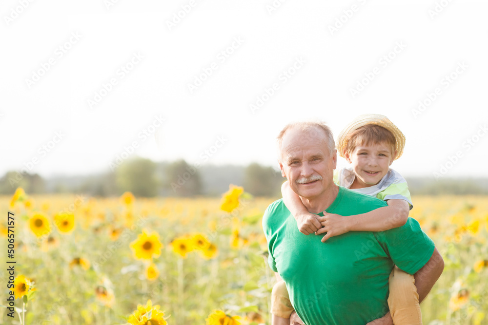 Obraz premium Concept of friendly family. grandfather and grandson spend time together in nature. Copy space Little child boy hugs grandpa On Walk in the summer outdoors. 