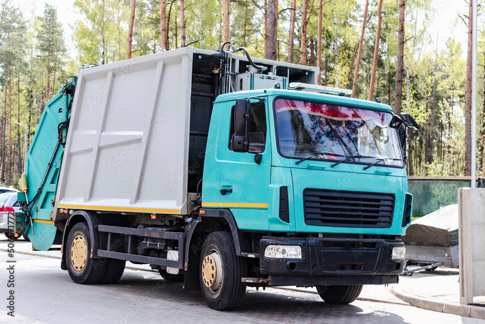 A garbage truck picks up garbage in a residential area. Loading mussar in containers into the car. Separate collection and disposal of garbage. Garbage collection vehicle.