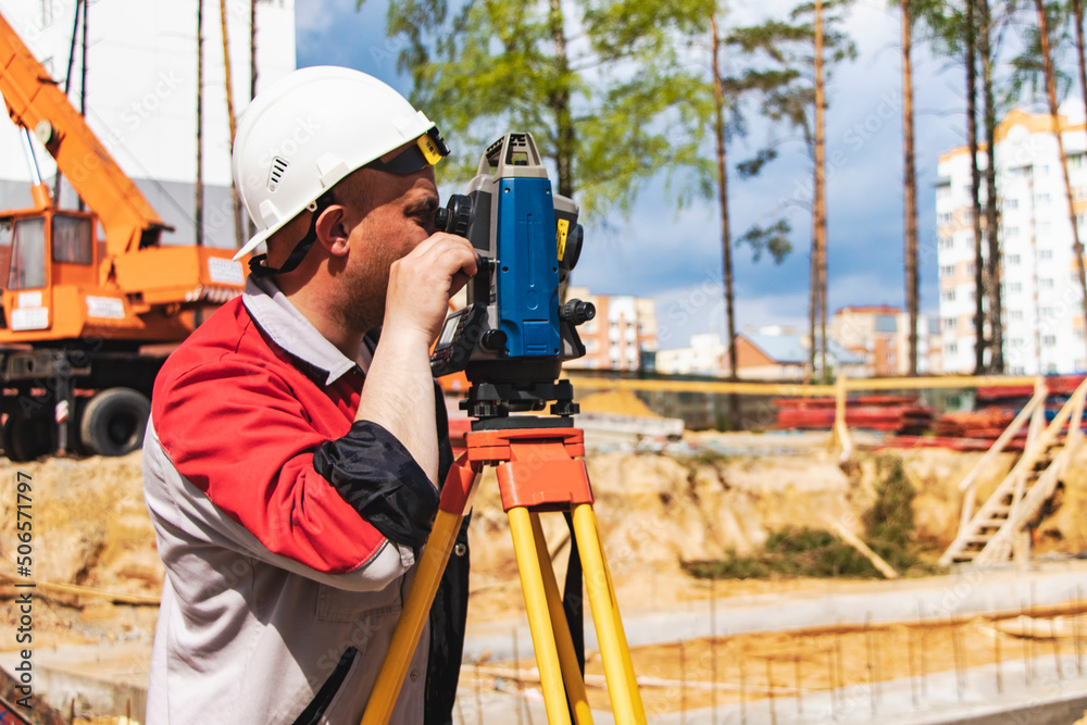 Construction of a residential area. Geodetic stakeout. Surveyor at a large construction site. A man with a tachometer during work. Makshader.