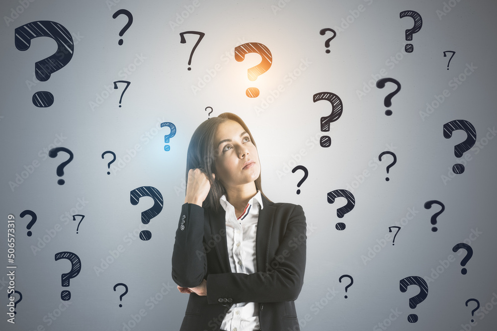 Searching for an answer concept with pensive young businesswoman on light wall background with black question marks Searching for an answer concept with pensive young businesswoman on light wall background with black question marks