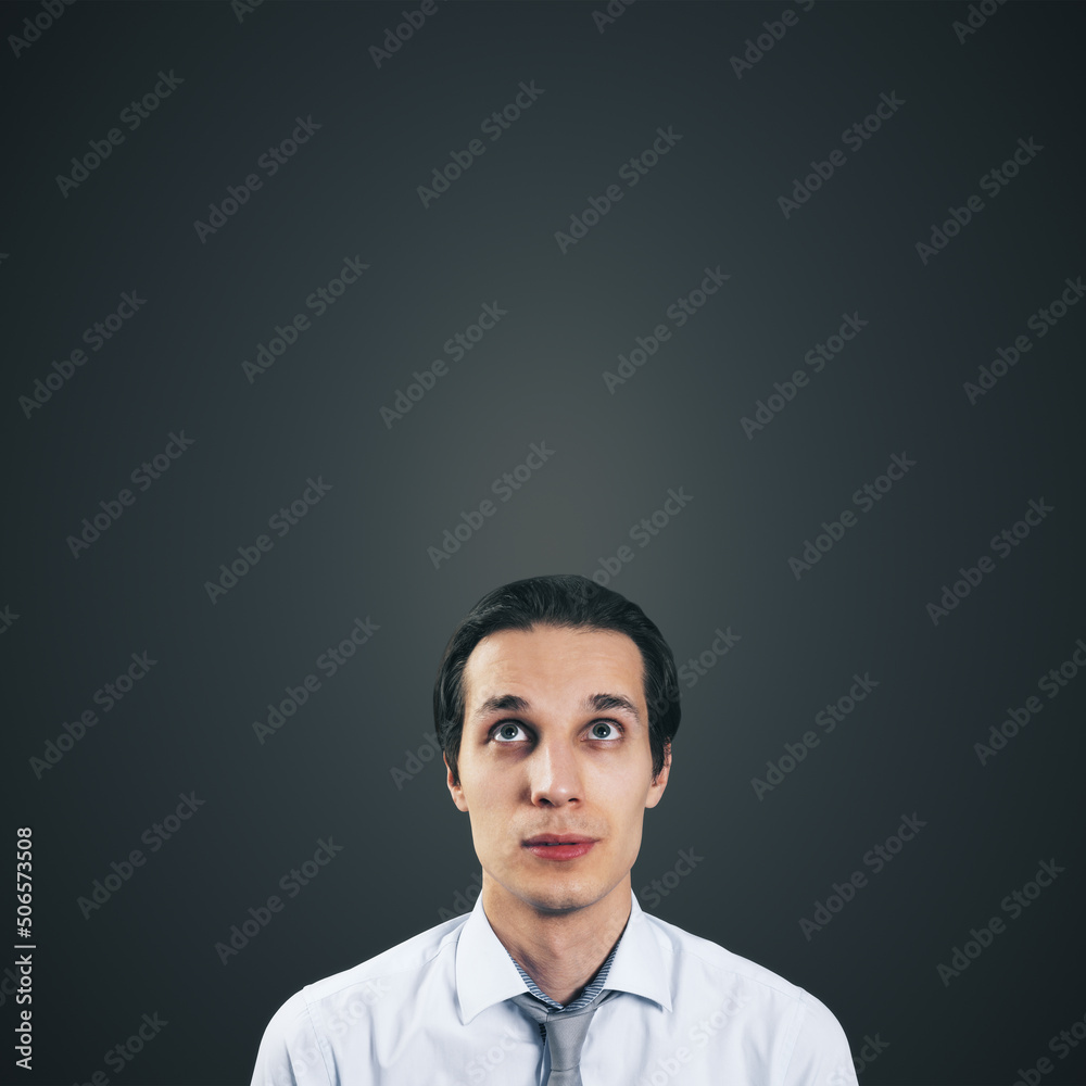 Man looking up in white shirt and tie isolated on blank dark grey background with empty space for your text or logo, mockup. Thinking and brainstorming concept, close up Man looking up in white shirt and tie isolated on blank dark grey background with empty space for your text or logo, mockup. Thinking and brainstorming concept, close up